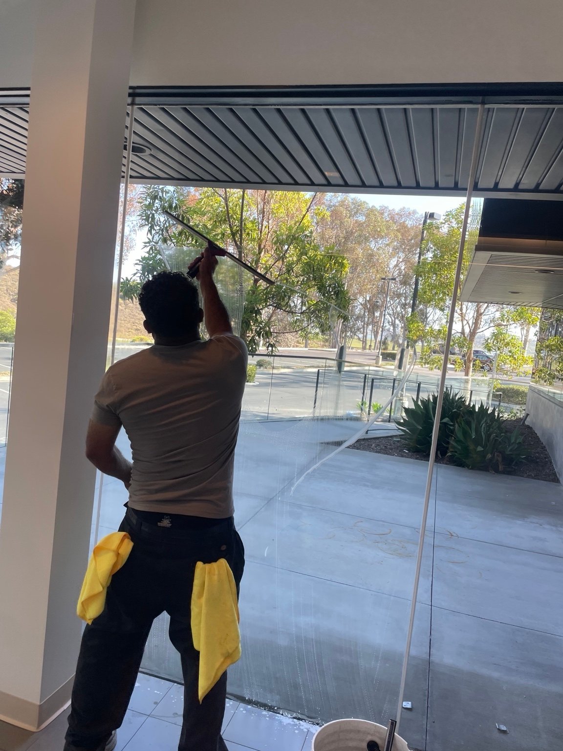 Evans Dynamic crew member cleaning commercial glass with a squeegee