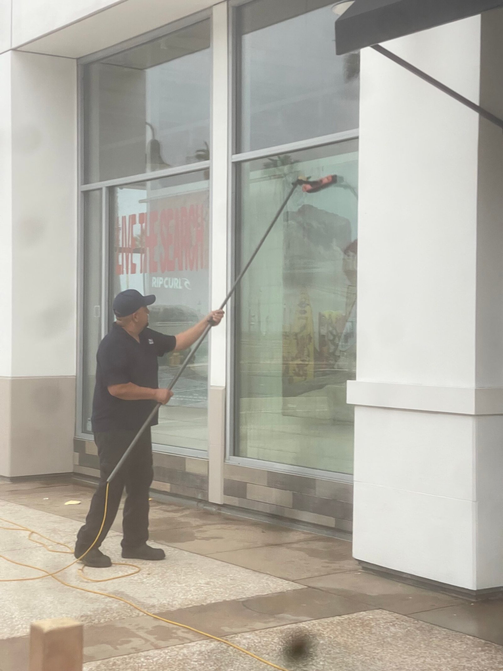 Evans Dynamic cleaning tall storefront windows with a water-fed pole